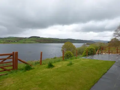 a view of a lake with a wooden fence at Ffynnon Gower in Llangower