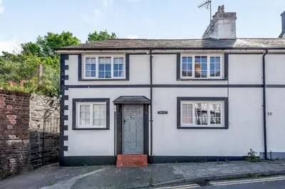 a white house with a blue door on a street at Kynaston Cottage in Aberdyfi