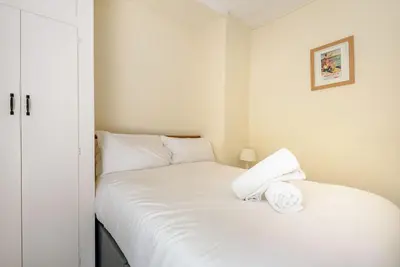 a white bed with two white towels on it at Kynaston Cottage in Aberdyfi