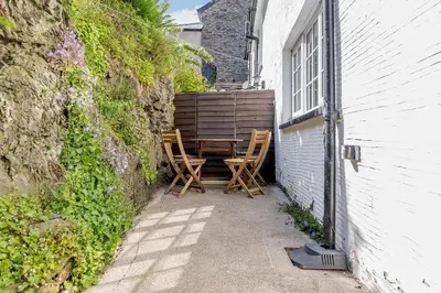 a patio with two chairs and a table next to a building at Kynaston Cottage in Aberdyfi