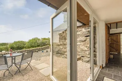 a sliding glass door leading to a patio with a table at Y Becws in Llanbedr
