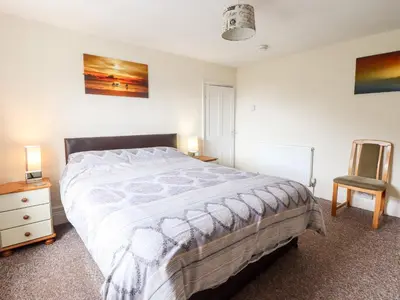 a bedroom with a large bed and a chair at 2 Isygraig in Corris