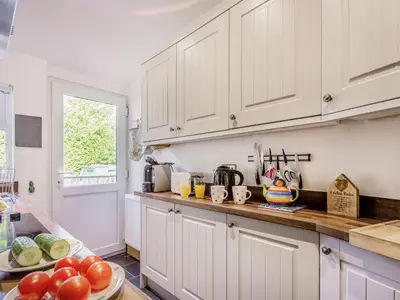 a kitchen with white cabinets and a plate of fruit at Bro Dawel in Dolgellau