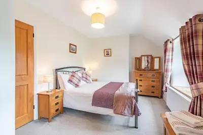 a bedroom with a bed and a dresser and a window at Waedog Bach in Llanfor