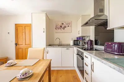 a kitchen with white cabinets and a wooden table at Waedog Bach in Llanfor