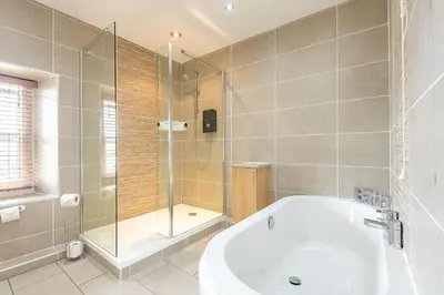 a bathroom with a tub and a glass shower at Waedog Bach in Llanfor