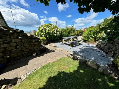 a picnic table in a garden with a stone wall at Hwylfa'r Groes in Dyffryn