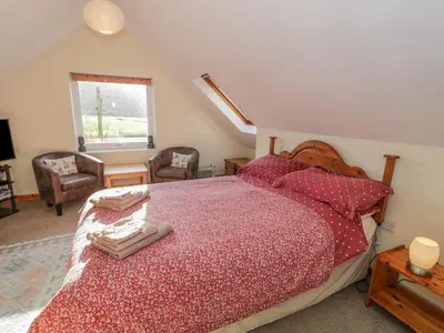 a bedroom with a bed with a red comforter at Bryn Melyn Artist's Cottage in Llanelltyd