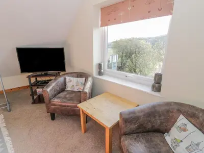 a living room with two chairs and a television at Bryn Melyn Artist's Cottage in Llanelltyd