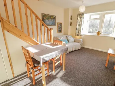 a living room with a staircase and a table and a couch at Bryn Melyn Artist's Cottage in Llanelltyd