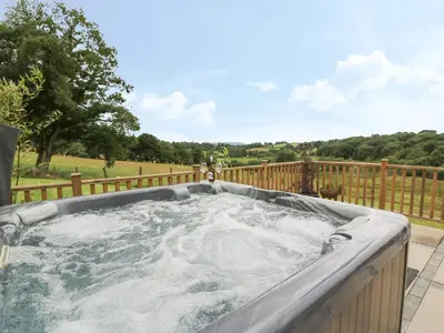 a hot tub on a deck with a fence at Pheasant Wood in Llandrindod Wells