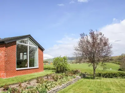 a red brick house with a window in a garden at Bryn Caer in Chirbury