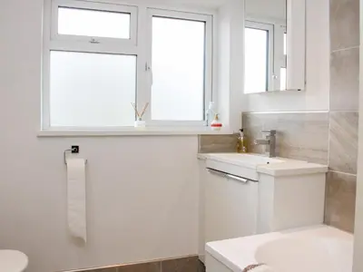 a white bathroom with a sink and a window at Bryn Caer in Chirbury