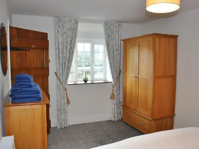 a bedroom with a bed and a dresser and a window at Hafan in Llanerfyl