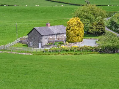 an old house in the middle of a green field at Hafan in Llanerfyl