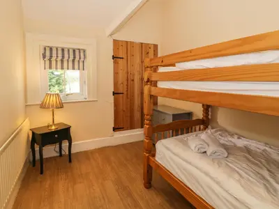 a bedroom with two bunk beds and a table with a lamp at The Mill House in Carrog