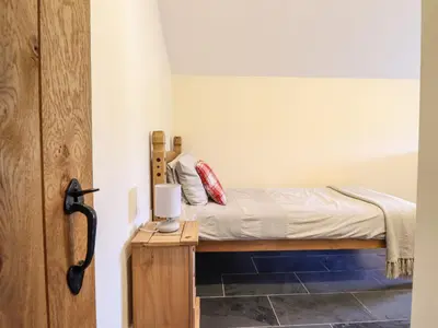 a small bedroom with a bed and a wooden table at Beudy Bach Barn in Llanuwchllyn