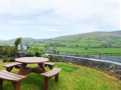 a picnic table and two benches in the grass at Arllen Fawr in Pen-y-bont-fawr