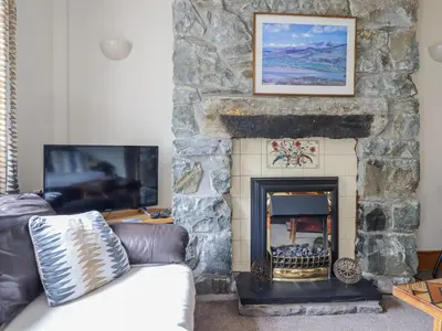 a living room with a stone fireplace at Cae Tanws Bach in Dolgellau