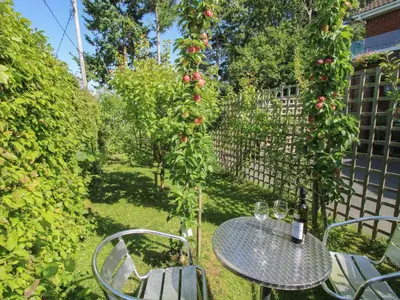 a table and chairs in a garden with an apple tree at Plum Hill Apartment in Oswestry