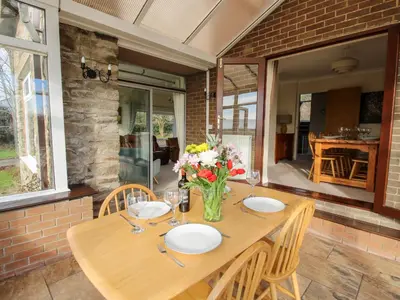 a wooden table with chairs and a vase of flowers at Bicton Lea in Acton