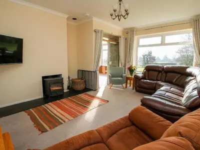 a living room with a leather couch and a fireplace at Bicton Lea in Acton