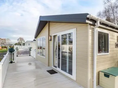 a small house with a large deck with a house at Clearview Lodge in Borth