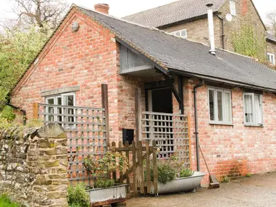 a brick house with a porch and a fence at Goosepond in Wistanstow