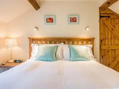 a bedroom with a large white bed with blue pillows at Borrowers Cottage in Condover