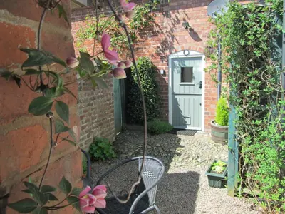 a garden with a chair in front of a house at Borrowers Cottage in Condover