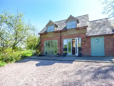 a red brick house with a blue garage at Gwdihw in Ifton Heath