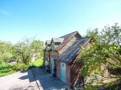 a small brick house with a garage on a driveway at Gwdihw in Ifton Heath