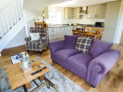 a living room with a purple couch and a table at Gwdihw in Ifton Heath