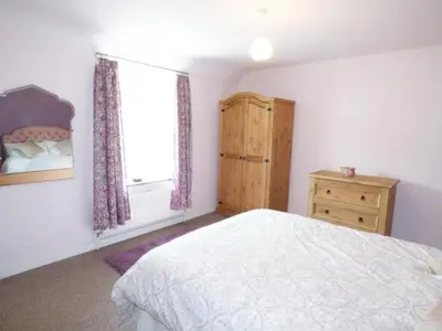 a bedroom with a bed and a window and a dresser at Y Bwythyn at Henfaes in Rhydymain