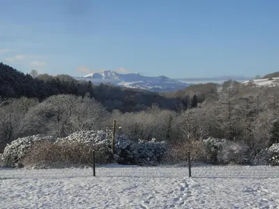 a snow covered field with trees and mountains in the background at Y Bwythyn at Henfaes in Rhydymain