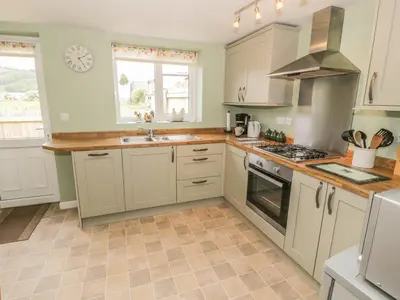 a kitchen with white cabinets and a stove top oven at Brickfield Cottage in Machynlleth