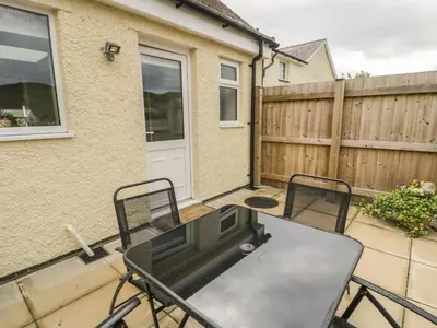 a patio with a table and chairs and a fence at Brickfield Cottage in Machynlleth
