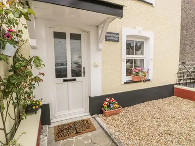 a white front door of a house with flowers in pots at Brickfield Cottage in Machynlleth