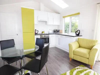 a kitchen with a glass table and a yellow chair at 73-The Lodge in Llanina