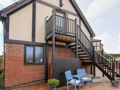 a house with a staircase and two blue chairs at The Wynnstead Annexe in West Felton