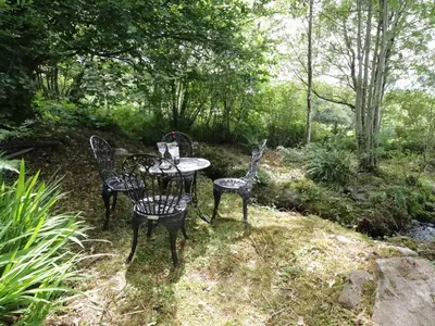 two chairs and a table in a garden at Moelfre Cottage in Llanbedr
