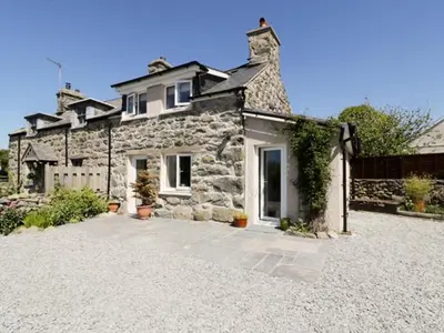a stone house on a gravel driveway at 2 Borthwen Cottages in Dyffryn