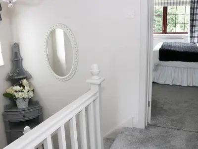 a white hallway with a mirror and a bed at Little Beeches in Selattyn