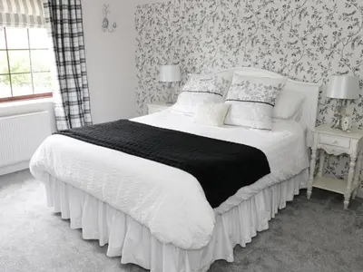 a bedroom with a bed with a black and white comforter at Little Beeches in Selattyn