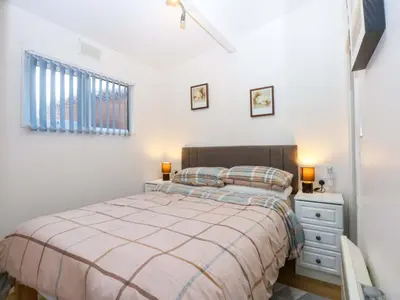 a bedroom with a bed and a dresser and a window at River's Nook in Llangynog