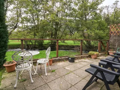 a patio with chairs and tables and a pond at River's Nook in Llangynog