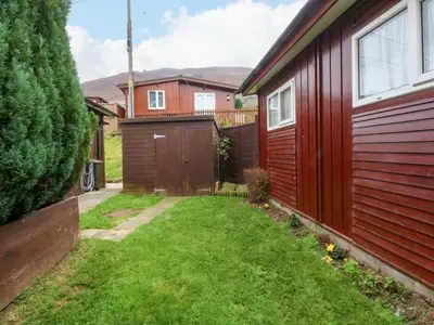 a yard next to a house with a fence at River's Nook in Llangynog