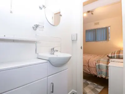 a white bathroom with a sink and a bed at River's Nook in Llangynog