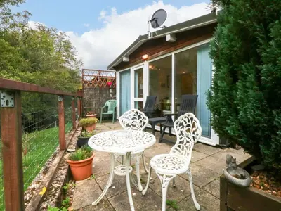 a patio with four chairs and a table and a house at River's Nook in Llangynog
