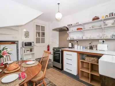 a kitchen with white cabinets and a table with chairs at 7 Bell Street in Talgarth